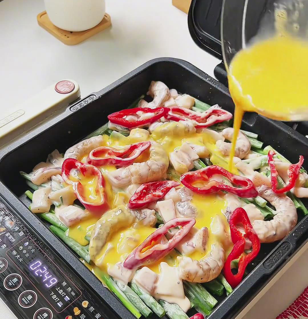 pour the beaten egg mixture evenly over the seafood and vegetables